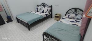 a bedroom with two beds and a bedskirts at ZIRA STAY PENARIK - Nuha Room in Kampong Ru Sepuloh