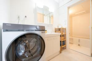 a washing machine in a white laundry room at HIKARIE Modern Stay Toyama in Toyama