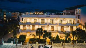 a white building with palm trees in front of it at Resol Hotel in Ksamil