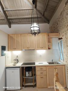 a kitchen with wooden cabinets and a chandelier at Suites-Xenonas "Alexandra's Coffee House" in Volímai +118 photos