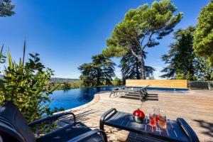 a patio with a table and chairs next to a lake at Domaine de ferrabouc in Mas-Saintes-Puelles