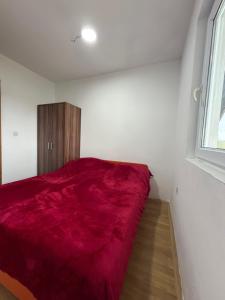 a bedroom with a red bed and a window at Vrba in Gacko