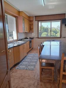 a kitchen with a table and chairs and a window at A Morada do Cuco in Piñor