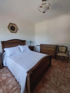 a bedroom with a large bed and a chair at A Morada do Cuco in Piñor