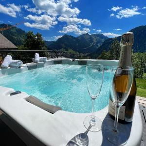 a hot tub with a bottle of champagne and two glasses at Chalet Familial Le Whymper 5 étoiles SPA Sauna Chatel in Châtel