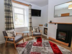 a living room with a fireplace and two chairs at Alt na Voir in Tomintoul