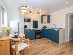 a kitchen with blue cabinets and a wooden table at Alt na Voir in Tomintoul