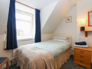 a bedroom with a bed with blue curtains and a window at Alt na Voir in Tomintoul