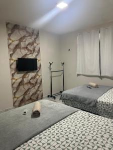 a bedroom with two beds and a tv on a wall at Pousada Nova Betânia in Mossoró