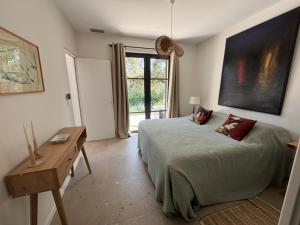 a bedroom with a bed and a table and a window at Villa Toscane in Meyreuil