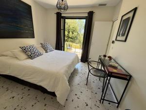a bedroom with a bed and a table and a window at Villa Toscane in Meyreuil