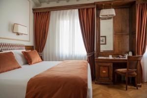 a bedroom with a bed and a desk and a mirror at Adler Cavalieri Hotel-Private Spa & Gym in Florence +60 photos
