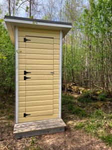 a outhouse with a yellow garage door in the woods at Ilmjärve Glamping Otepää in Ilmjärve