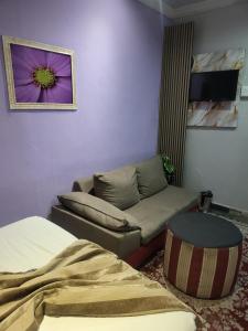 a living room with a couch and a bed and a purple wall at Tshilidzi Guest House in Pretoria