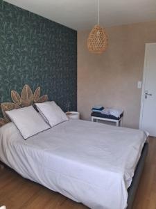 a bedroom with a white bed with a green wall at Le jardin aux iris in Tonnerre