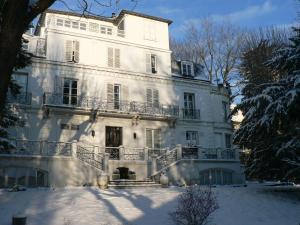 a large white house with snow on the ground at Chambre Eugénie in Saint-Cloud