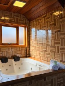 a large bath tub in a room with a window at Chales Vale da Nascente in Monte Verde +56 photos
