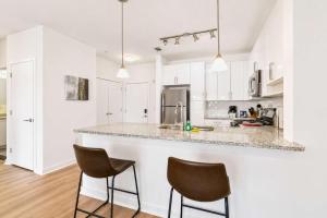 a white kitchen with two chairs and a counter at Modern Apt Downtown with Pool in Stamford