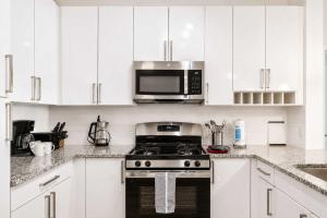 a white kitchen with a stove and a microwave at Modern Apt Downtown with Pool in Stamford +15 photos