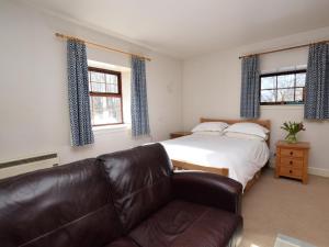 a bedroom with a bed and a leather couch at 1 Bed in Applecross oc-ca186 in Applecross