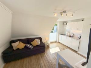 a living room with a couch and a kitchen at Westerheide 51, App 1 in Wenningstedt