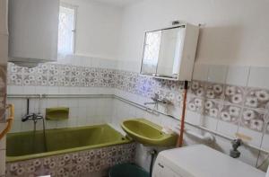 a bathroom with a green tub and a sink at Rózsa Ház in Mélykút
