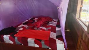 a red and white bed in a purple room at War Nyampun Homestay in Waisai +7 photos