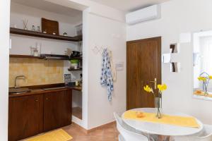 a kitchen with a table with a vase of flowers on it at Casa Rica in Alghero +11 photos