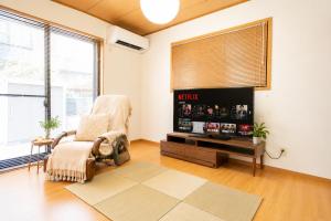 a living room with a chair and a flat screen tv at Max13ppl Family-Friendly , 110sqm , SpaciousLiving&4BRM , LongStay OK , 2CarPark , 25min to NAGOYA & LEGO & Outlet in Yatomi 