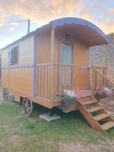 an old wooden trailer with a porch and flowers at Roulotte bohème in Chazelles +6 photos