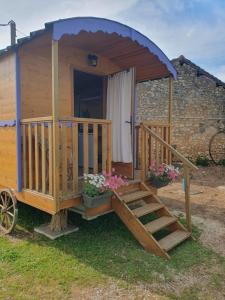 a wooden out house with a porch and stairs at Roulotte bohème in Chazelles