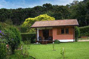 a small house with two chairs in a yard at Chalé das Flores - Refúgio com clima de chácara no Centro de Gonçalves in Gonçalves