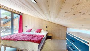 a bed in a room with a wooden ceiling at MONTCHAVIN - Résidence Hôtelière Bellecôte 4 étoiles in La Plagne Tarentaise