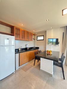 a kitchen with a table and a white refrigerator at Villa Visgo Itacaré in Itacaré