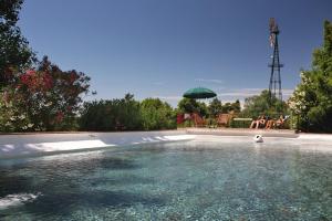 a swimming pool with people sitting under a green umbrella at Quinta Da Praia Das Fontes in Alcochete