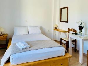 a bedroom with a bed with a table and a desk at Limnes Seaside Combo in Ligaridia