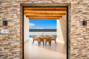 a dining room with a table and chairs and a brick wall at Villa Salty Sun 6 in Kremasti