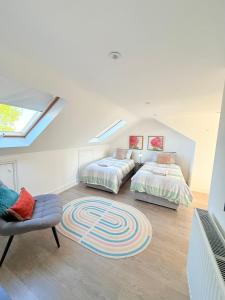 a attic bedroom with two beds and a chair at Large 3 bed 2 bath modern apartment in Finchley