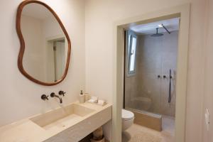 a bathroom with a sink and a toilet and a mirror at Eos Milos House in Pollonia +40 photos