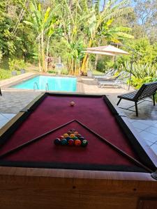 a pool table with balls on it next to a swimming pool at Sitio Chacara Piscina Aquecida Acesso Asfaltado in Juquitiba