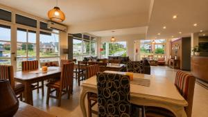 a restaurant with tables and chairs and windows at Mojomar Pinamar Hotel in Pinamar
