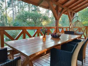 a wooden table with chairs on a wooden deck at W Sosnowym Lesie Pluski in Pluski