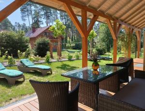 a patio with a table and chairs in a yard at W Sosnowym Lesie Pluski in Pluski
