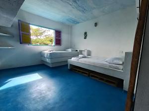 two beds in a room with blue floors and a window at Casa Violeta Beach House in Rincón