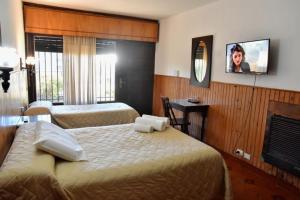 a hotel room with two beds and a tv on the wall at Residencial Garcia in Embalse