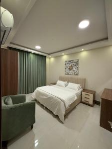 a bedroom with a large bed and a chair at Taqah Beach Front Apartment in Ţāqah