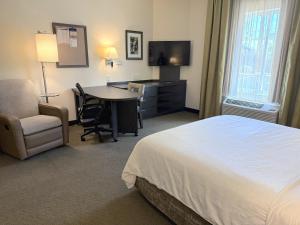 a hotel room with a bed and a desk and a chair at Candlewood Suites - Jacksonville - Mayport by IHG in Jacksonville +46 photos