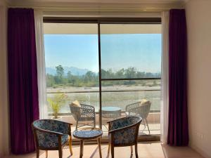 a room with a table and chairs and a large window at Eternal Bliss By Ganga Blessing in Rishīkesh