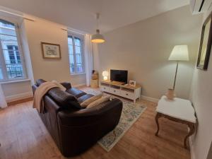 a living room with a leather couch and a television at Maison de Centre ville in Limoux