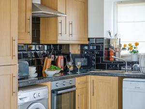 a kitchen with wooden cabinets and a counter top at Hayloft - Ukc4678 in Clynnog-fawr